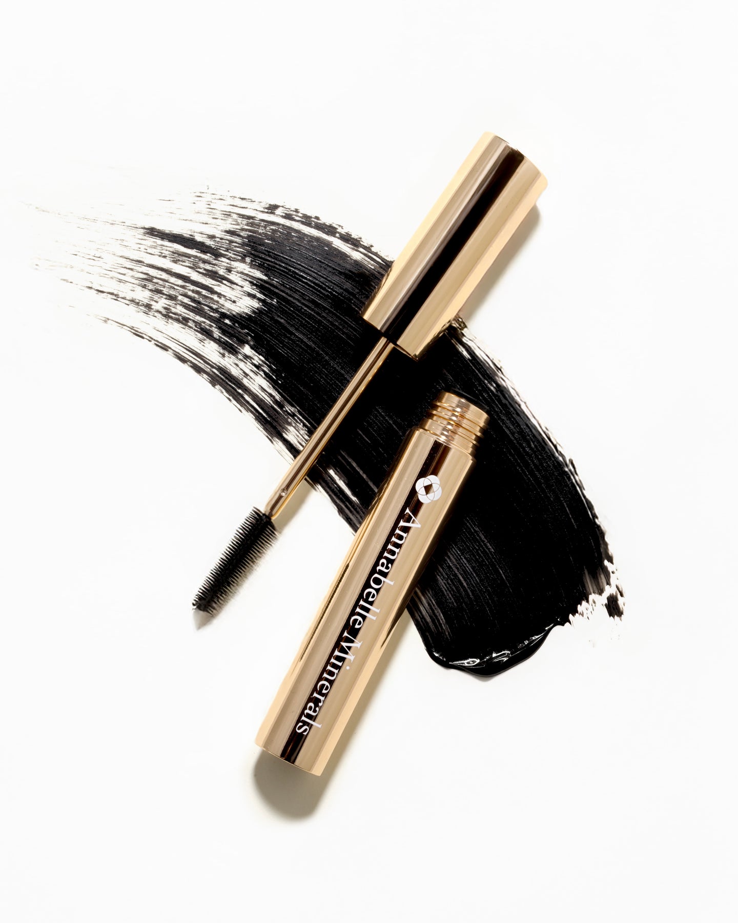 Czarny tusz do rzęs Serum Mascara Annabelle Minerals w eleganckim złotym opakowaniu z leżącą obok szczoteczką