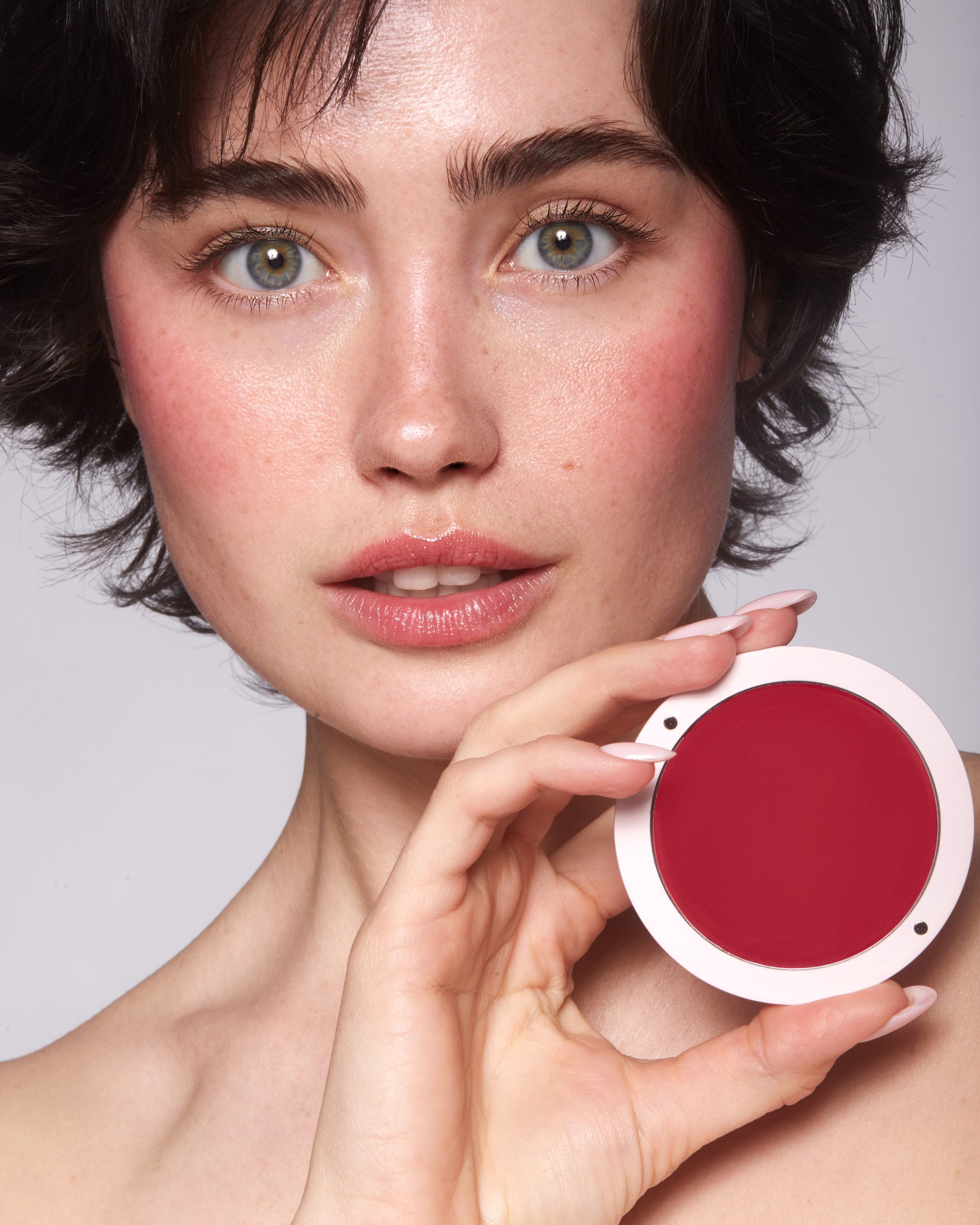 Kobieta z ciemnymi włosami i jasną, piegowatą skórą z makijażem kremowym różem Red Velvet Annabelle Minerals