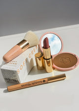 Różnorodne kosmetyki Annabelle Minerals: pędzel flat top, kompaktowy bronzer mineralny, szminka. krem Soft Cream i kredka do oczu w stylowej aranżacji