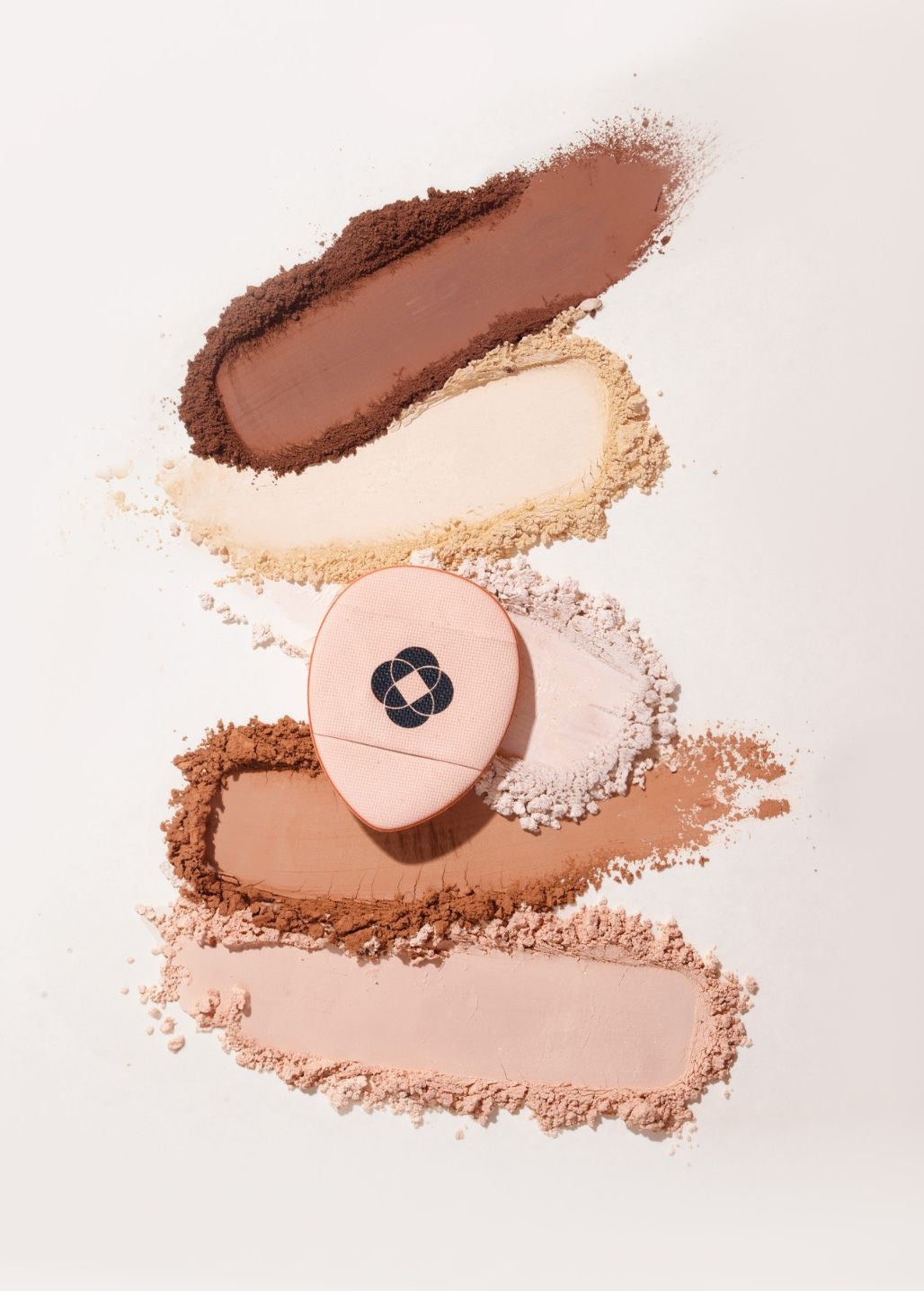 Mini aplikator Annabelle Minerals wśród swatchy podkładów mineralnych w różnych odcieniach