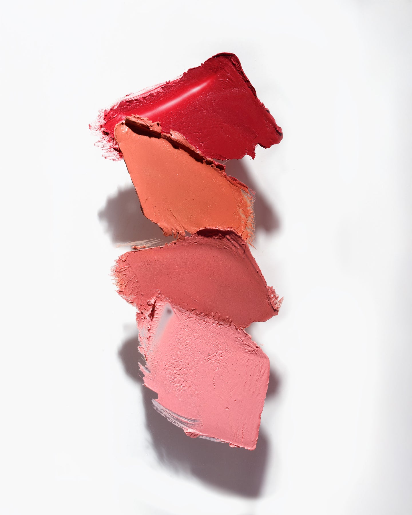 Swatche kremowych różów Blush Balm Annabelle Minerals w odcieniach czerwieni i różu w gradiencie na białym tle