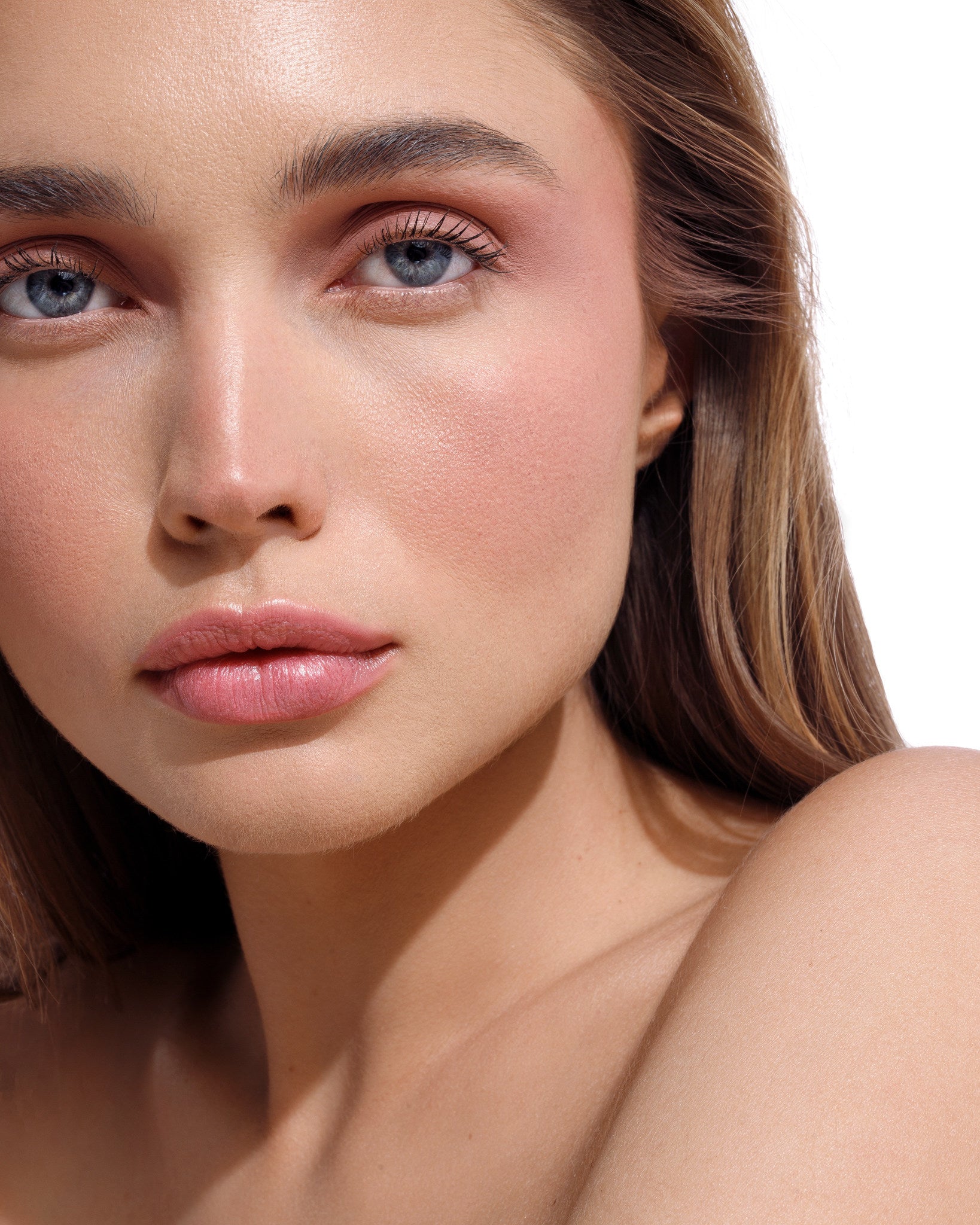Kobieta z długimi prostymi włosami, niebieskimi oczami i pełnymi ustami w naturalnym świetle w makijażu kosmetykami mineralnymi Annabelle Minerals