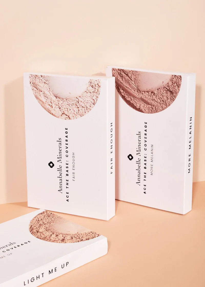 Trzy pudełka mini kosmetyków Annabelle Minerals w minimalistycznym designie na delikatnym brzoskwiniowym tle